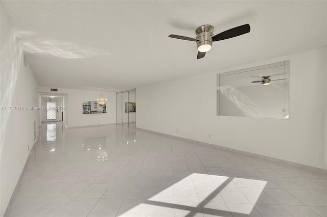 unfurnished room with light tile patterned floors, ceiling fan with notable chandelier, and a textured ceiling