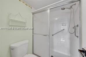 bathroom featuring toilet and a shower with shower door