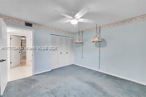 unfurnished bedroom featuring ceiling fan, a closet, and dark colored carpet