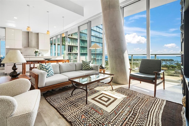 interior space featuring a water view, light wood-type flooring, and a wall of windows