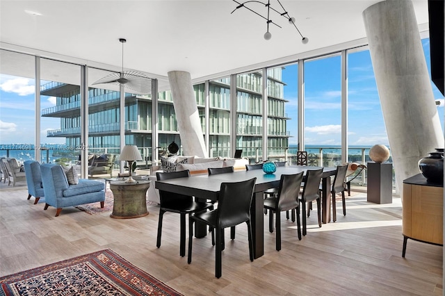 dining room with a water view, light hardwood / wood-style floors, and expansive windows