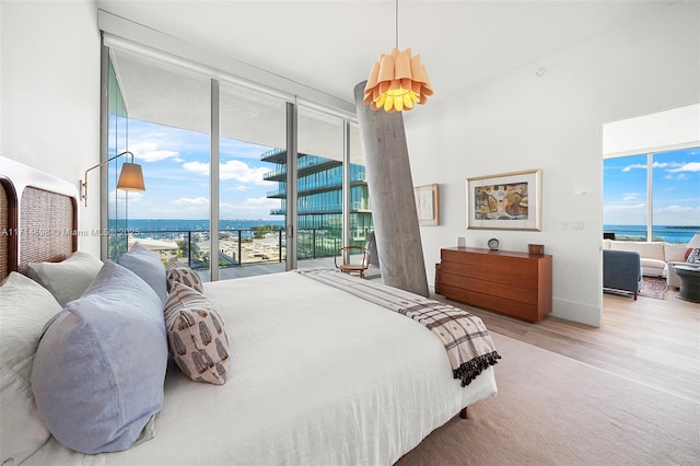 bedroom with a water view, wood-type flooring, access to exterior, and multiple windows