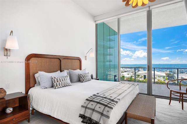 bedroom with floor to ceiling windows, a water view, and access to outside