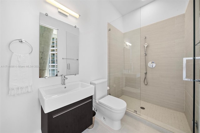 bathroom featuring tile patterned floors, toilet, vanity, and a shower with shower door