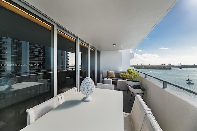 balcony featuring outdoor dining space and a water view