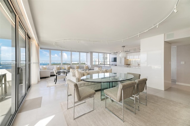 dining space with a wall of windows, a water view, and track lighting