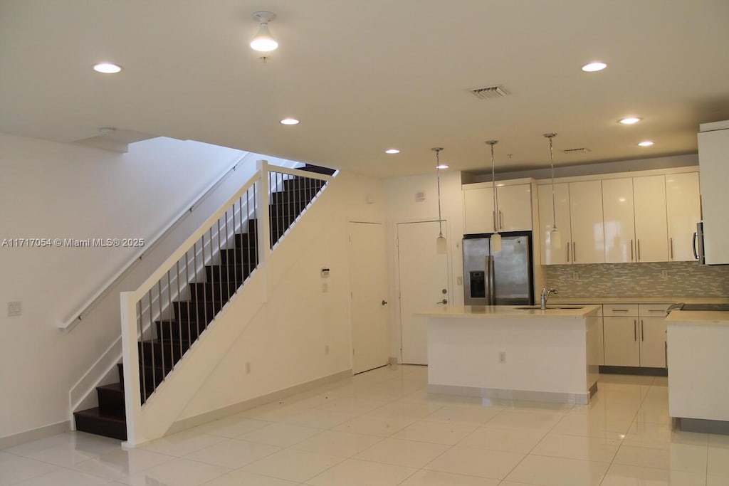 kitchen featuring hanging light fixtures, white cabinetry, light tile patterned floors, a kitchen island, and stainless steel fridge with ice dispenser