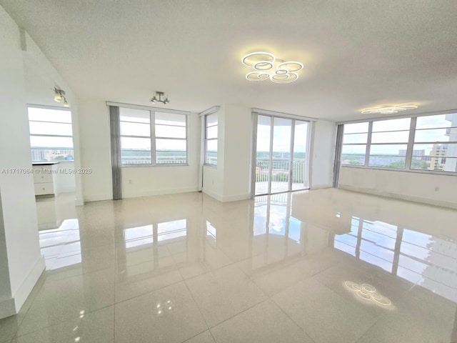 empty room featuring tile patterned floors, baseboards, and a textured ceiling