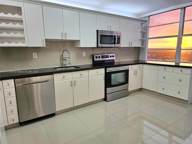 kitchen featuring dark countertops, a sink, appliances with stainless steel finishes, and open shelves