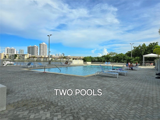 community pool with a city view, a patio, and a water view