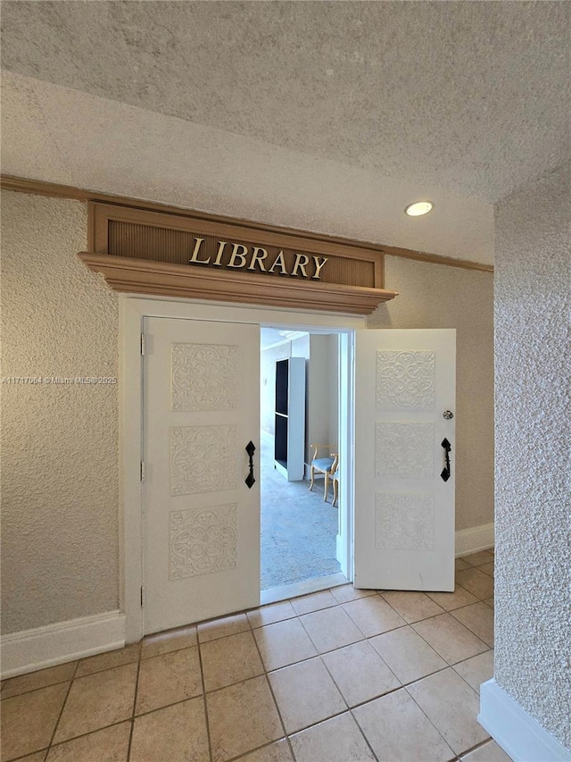 entrance foyer featuring light tile patterned floors, a textured ceiling, and baseboards