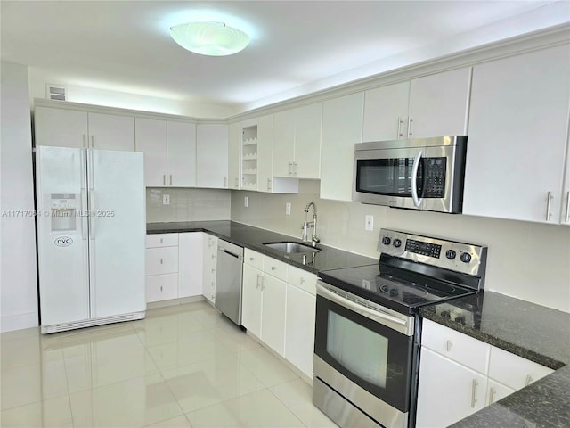 kitchen with visible vents, dark stone counters, a sink, decorative backsplash, and appliances with stainless steel finishes