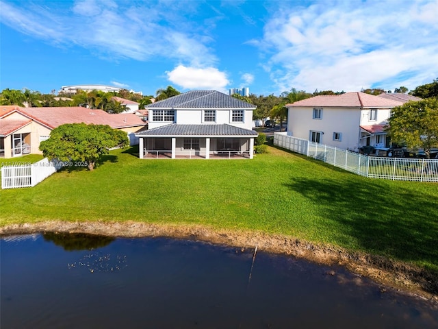 rear view of property featuring a sunroom, a water view, and a yard