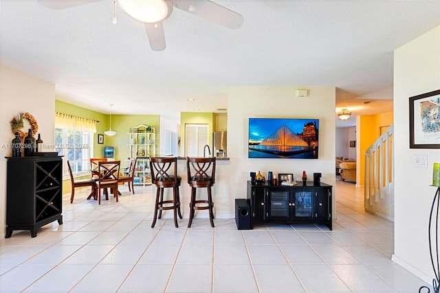 tiled living room with ceiling fan and a textured ceiling