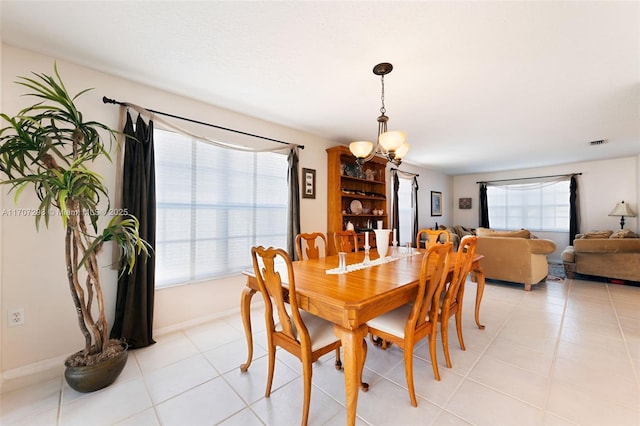 dining space with light tile patterned floors, plenty of natural light, and a notable chandelier