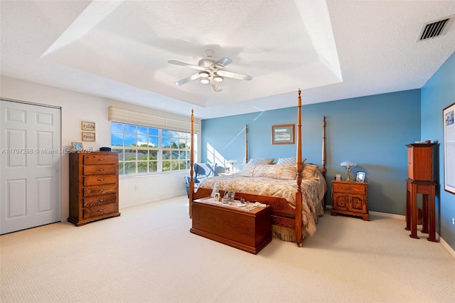 bedroom with a tray ceiling, ceiling fan, light colored carpet, and a textured ceiling