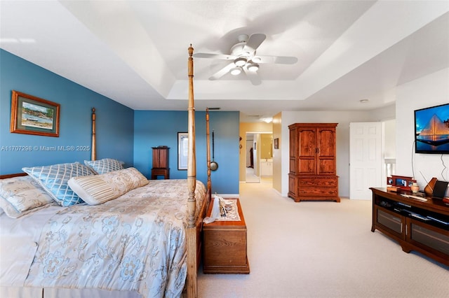 bedroom featuring a raised ceiling, ceiling fan, and light colored carpet