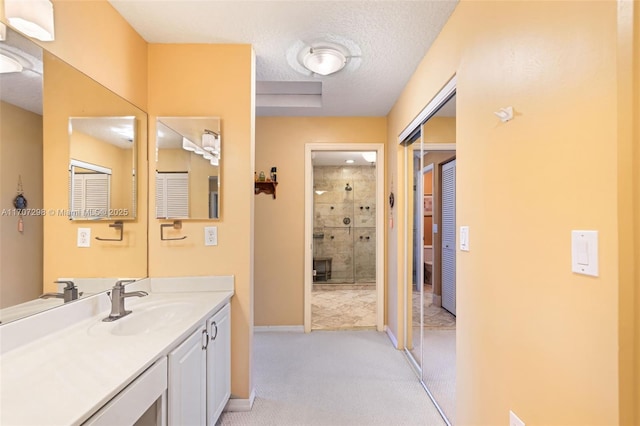 bathroom featuring vanity, a tile shower, and a textured ceiling