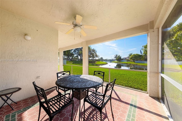 sunroom featuring ceiling fan and a water view