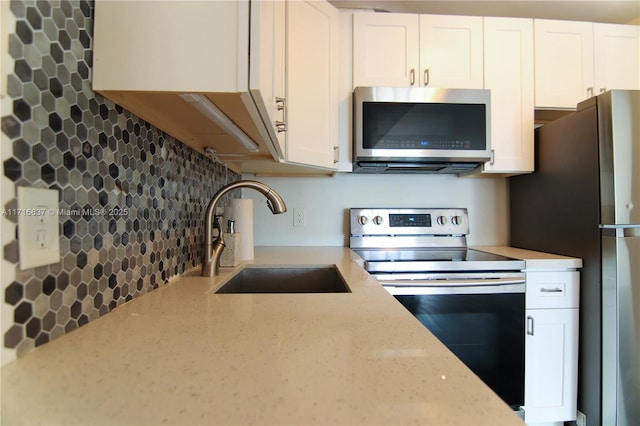 kitchen with decorative backsplash, white cabinetry, sink, and appliances with stainless steel finishes