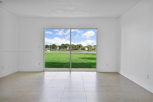 tiled empty room featuring a textured ceiling