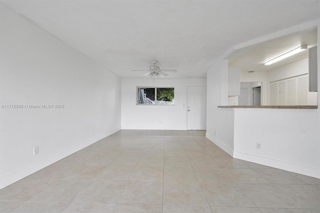 unfurnished room featuring ceiling fan, light tile patterned flooring, and a textured ceiling