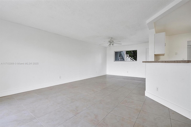 interior space featuring ceiling fan, light tile patterned floors, and a textured ceiling