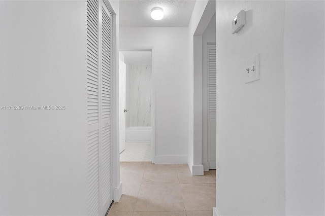 hallway with light tile patterned flooring and a textured ceiling