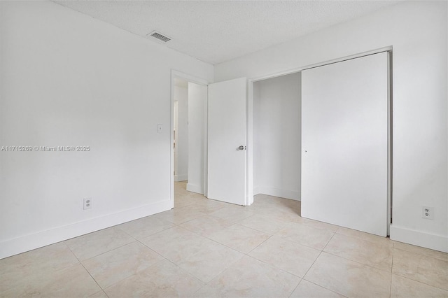 unfurnished bedroom featuring light tile patterned floors, a textured ceiling, and a closet