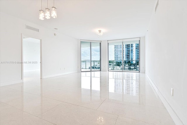 spare room with expansive windows, visible vents, and baseboards