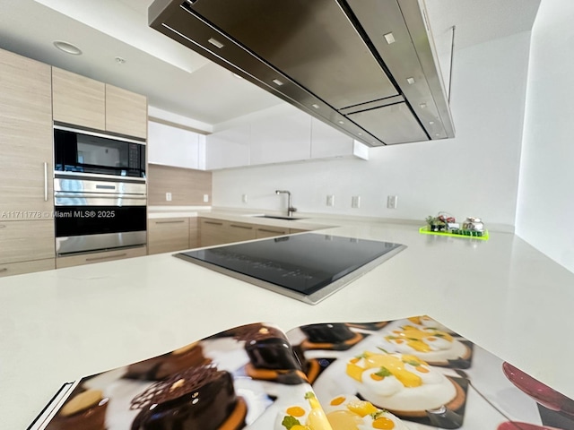 kitchen with a sink, black appliances, light countertops, and under cabinet range hood