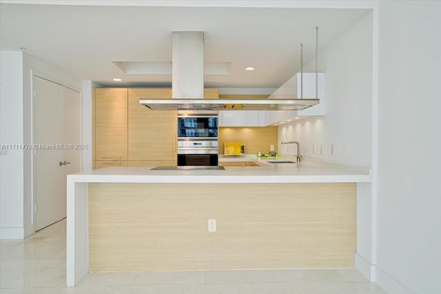 kitchen with backsplash, light countertops, a sink, and a peninsula