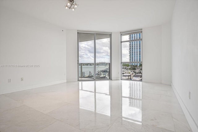 empty room featuring expansive windows and baseboards