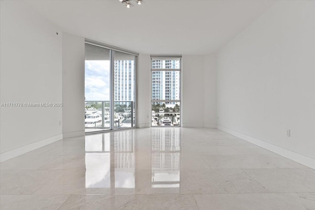 empty room featuring expansive windows and baseboards