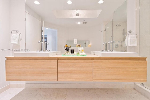 full bathroom with double vanity, a stall shower, visible vents, a raised ceiling, and a sink