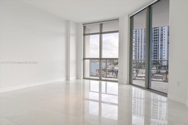 spare room featuring baseboards and floor to ceiling windows