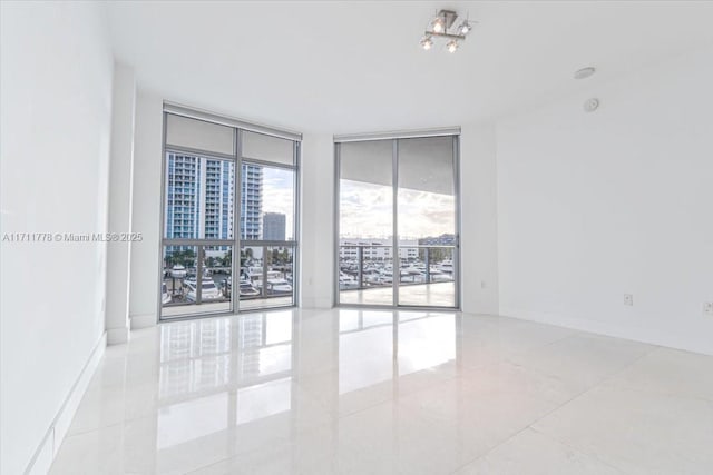 empty room with a wall of windows and baseboards