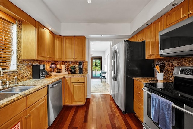 kitchen featuring sink, dark wood-type flooring, tasteful backsplash, light stone counters, and appliances with stainless steel finishes