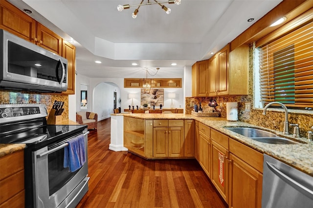 kitchen with kitchen peninsula, appliances with stainless steel finishes, sink, decorative light fixtures, and a chandelier