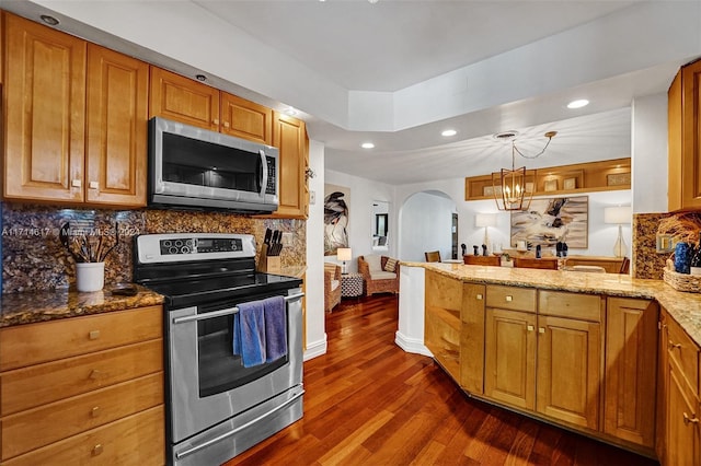 kitchen with backsplash, hanging light fixtures, light stone counters, stainless steel appliances, and a chandelier