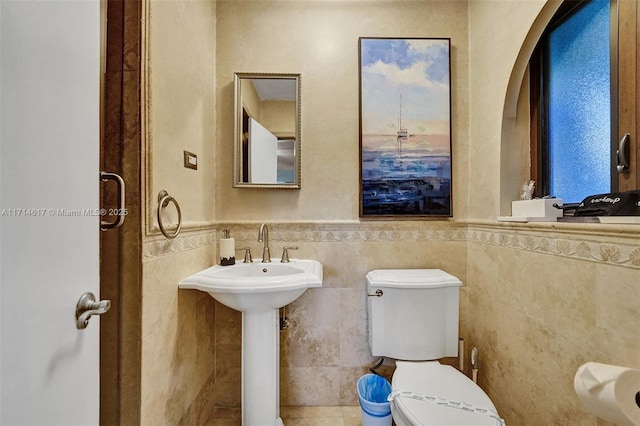 bathroom featuring toilet, tile walls, and sink