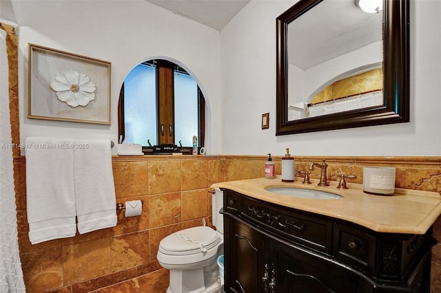 bathroom with vanity, toilet, and tile walls