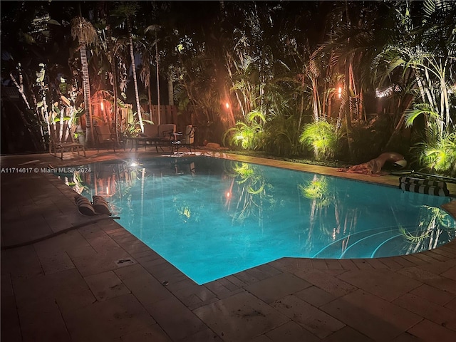 pool at night with a patio area