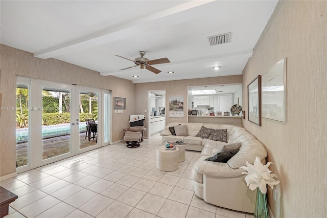 tiled living room with beamed ceiling, ceiling fan, and french doors