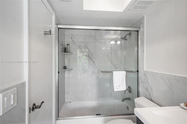 full bathroom with toilet, vanity, tile walls, and combined bath / shower with glass door