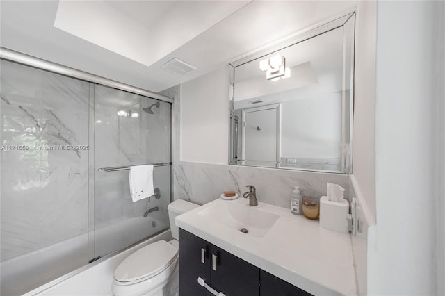 full bathroom with backsplash, bath / shower combo with glass door, vanity, tile walls, and toilet