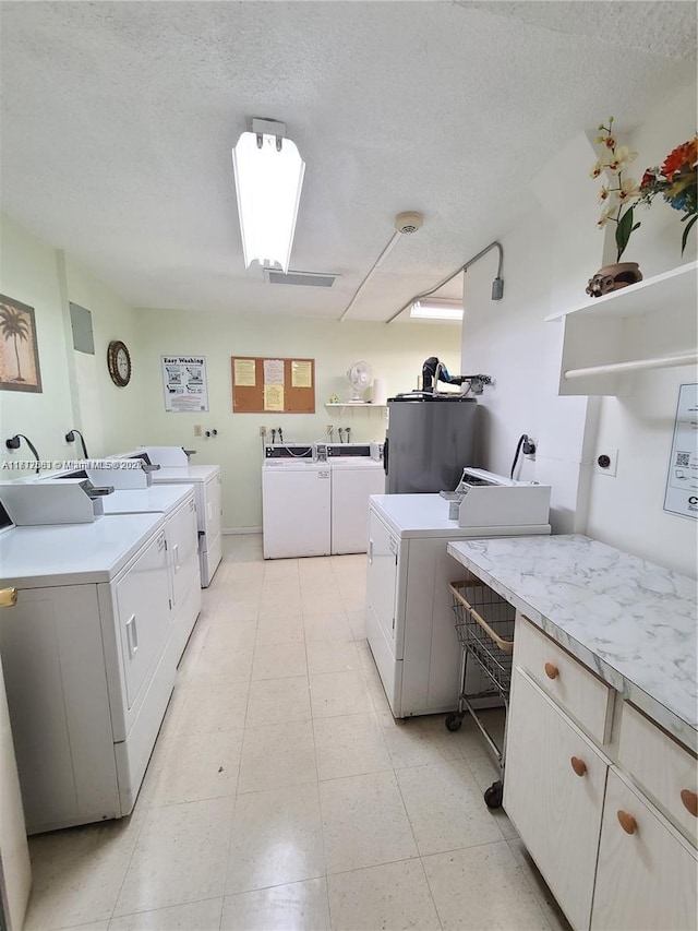 clothes washing area with washing machine and clothes dryer, water heater, and a textured ceiling