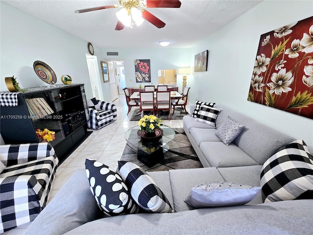 living room with ceiling fan, a textured ceiling, and light tile patterned floors