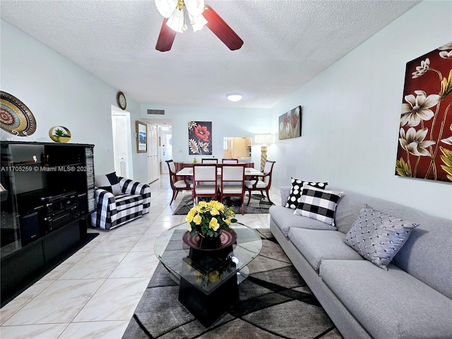 living room with a textured ceiling, light tile patterned floors, and ceiling fan