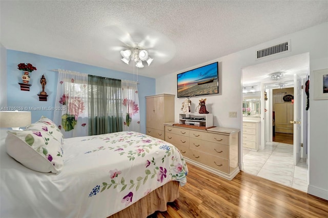 bedroom with ceiling fan, a textured ceiling, and light wood-type flooring